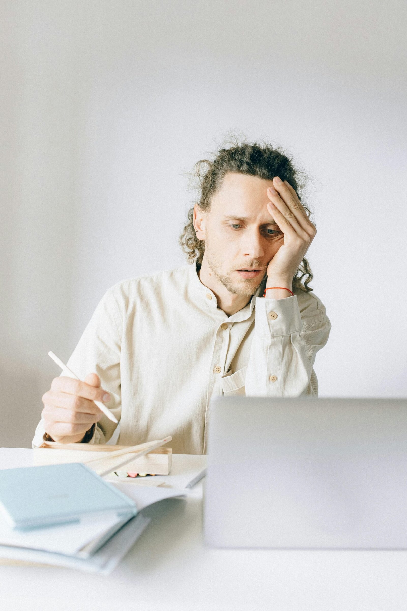 Young man overwhelmed by work at his desk, showing stress and fatigue.